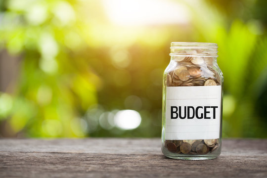 BUDGET word with coin in glass jar with Savings and financial investment concept.