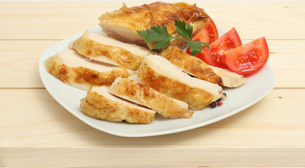 Grilled chicken fillet wit tomato on plate on wood background