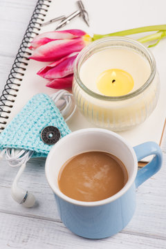Open notebook, coffe, candle, earpods and tulip