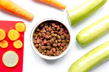 Dry dogfood with sliced vegetables on table background top view