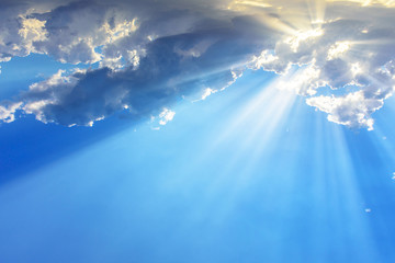 Fototapeta premium Sun light rays or beams bursting from the clouds on a blue sky. Spiritual religious background.