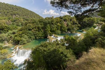 Fototapeta na wymiar Scenic view of waterfalls, cascades and lush foliage at the Krka National Park in Croatia. Viewed slightly from above.