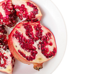 Broken red ripe pomegranates in white plate on white background
