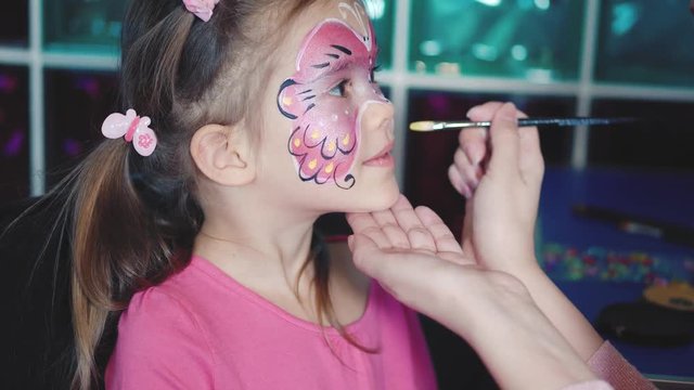 Painter makes butterfly shape at girl's face