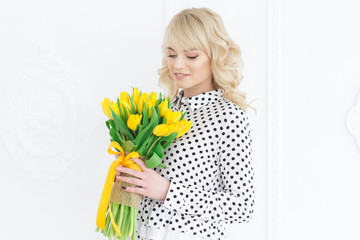 March 8 - International Women's Day. Young blond woman with bouquet of bright spring tulips