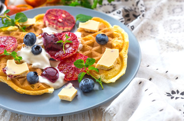 Fototapeta na wymiar Belgium waffles with blueberry, blood orange, whipped cream. Breakfast