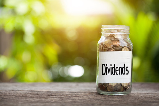 Dividends word with coin in glass jar with Savings and financial investment concept.