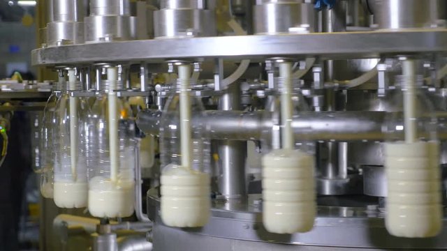 Milk pouring into plastic bottles at a food factory. 4K.