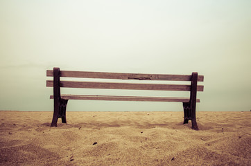 Old empty bench stands on sandy beach at a dull evening, Malia, Crete, Greece