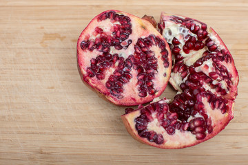 Broken red ripe juicy pomegranates on wooden table.