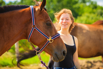 Jockey young girl petting brown horse