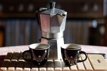 Two coffee cups, coffee pot and wooden cutting board in the kitchen, soft and selective focus