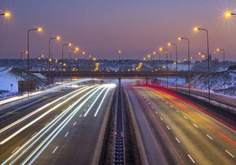 Fototapeta na wymiar Car light beams on highway at sunset