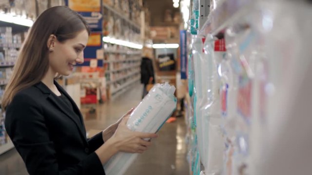 woman buys diapers at the supermarket, young mom mother shopping