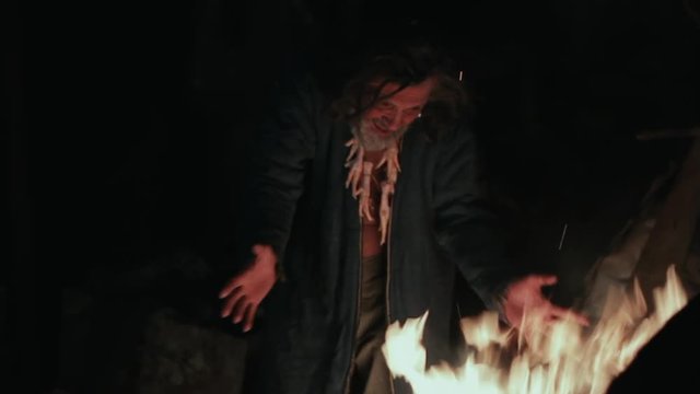 The old shaman dances around the fire
