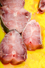 Fish stakes on yellow plate ready to be covered in bread crumbs