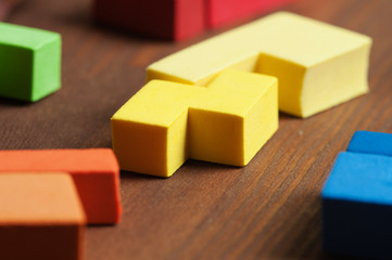 On a dark wooden table is the designer, puzzle, tetris elements of various shapes and sizes!