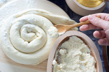 Female hand picking up molten cheese from wooden bowl