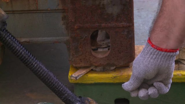 An operator turning the twistlock on the vast deck of a container ship. The twistlock and corner casting together form a standardized rotating connector for securing shipping containers.