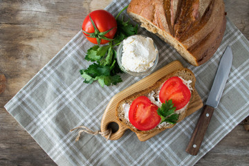 Sandwich of crispy bread, fresh tomatoes, cream cheese with herbs