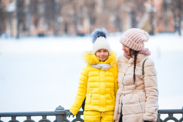 Little adorable girl with her mother skating on ice-rink