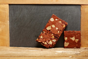 The brownie cake put on the hardwood among the slate board background represent the bakery and food concept related idea.
