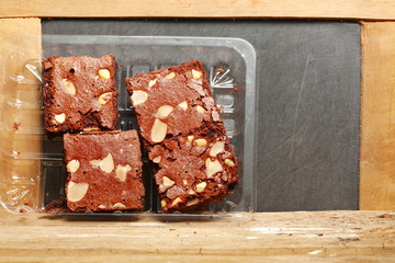 The brownie cake put on the hardwood among the slate board background represent the bakery and food concept related idea.