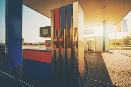 Wide Angle Shooting Of Covered Blue And Red Petrol And Gas Station With Multiple Pump Fuel Dispensers, Digital Screen With Red Digits, Tiled Floor Of Paving Stone On Warm Sunny Summer Day