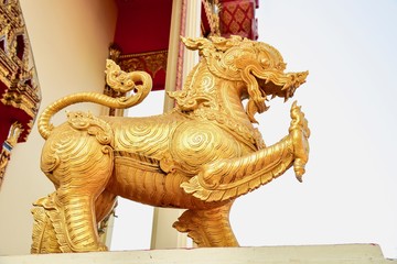 Fototapeta na wymiar Golden Singha Sculpture at the Entrance to a Buddhist Temple