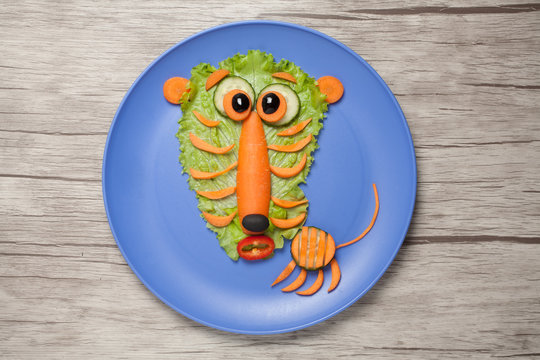 Astonished tiger made of salad and carrot on plate and table