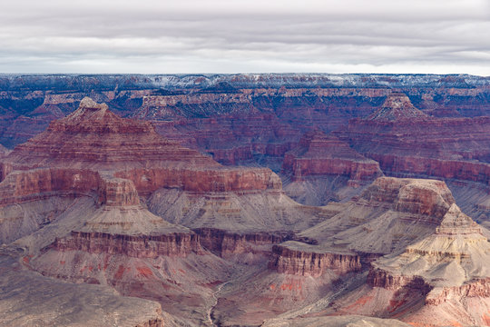 Panoramic view of the Grand Canyon in winter, portraying the colorful formations of the canyon's north side. The top edge of the canyon sports a thin stripe of snow from the just concluded storm. 