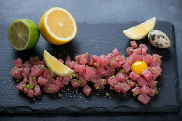 Close-up of tuna tartare with quail egg yolk, lemon and lime, selective focus