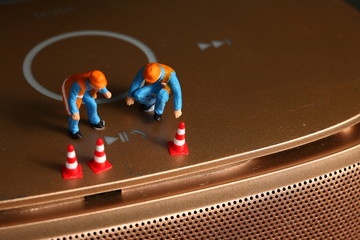 The round power button of the loudspeaker with maintenance miniature figure plastic model represent...