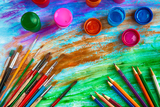 Artistic brushes, pencils and colored ink on colored background of avant-garde