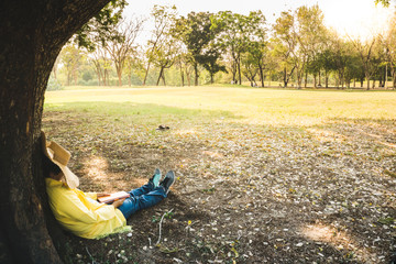 women sleeping under the tree with book in her hand at a upcountry park