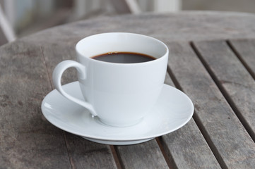 white cup of coffee on wooden table, soft focus