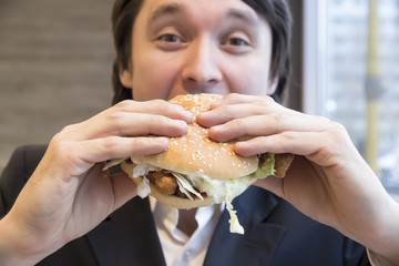 Man in business suit eating hamburge