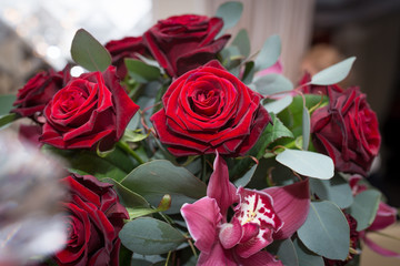Wedding detail. Fresh red roses, orchids and eucalyptus in the arrangement
