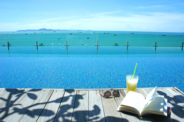 Naklejka premium relax cocktail book sun glass at swimming pool island view