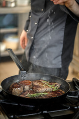 Chef putting salt for cooking meat
