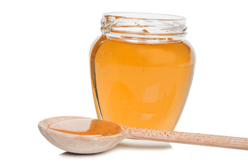 Bank full of yellow liquid honey with a wooden spoon