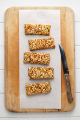 Homemade energy granola bars on wooden cutting board with knife. - 139189597