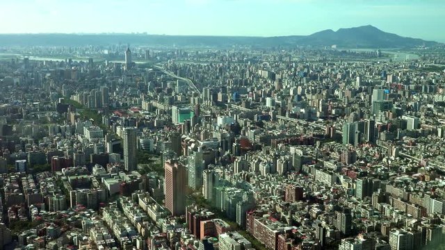 Landscape of Taipei City with skyscrapers and tall buildings, there are mountains on the horizon, Pan. 4K