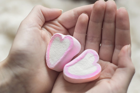 Marshmallow in the shape of a heart on the palms. The concept of love and fidelity