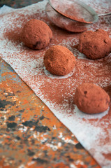 Dark chocolate truffles covered with cocoa powder on a rusty background. Overhead view, 