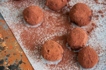 Dark chocolate truffles covered with cocoa powder on a rusty background. Overhead view, 