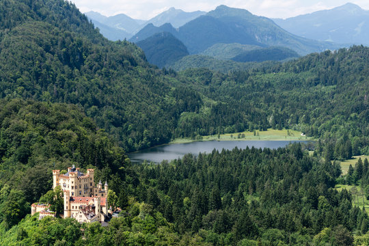 View from top to Hohenschwangau Castle (Schloss) and Alpsee lake from the mountain, Alps and trees on background, Fussen, Bavaria , Germany