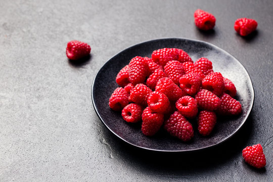 Fresh raspberries on a black bowl Slate background