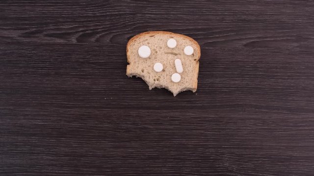A piece of bread with pills. Eating pills on toast. Top view. Stop motion