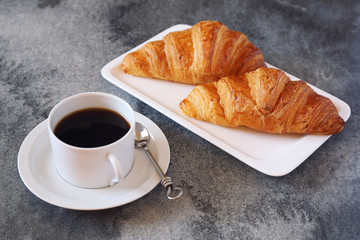 Two fresh croissants and cup of coffee